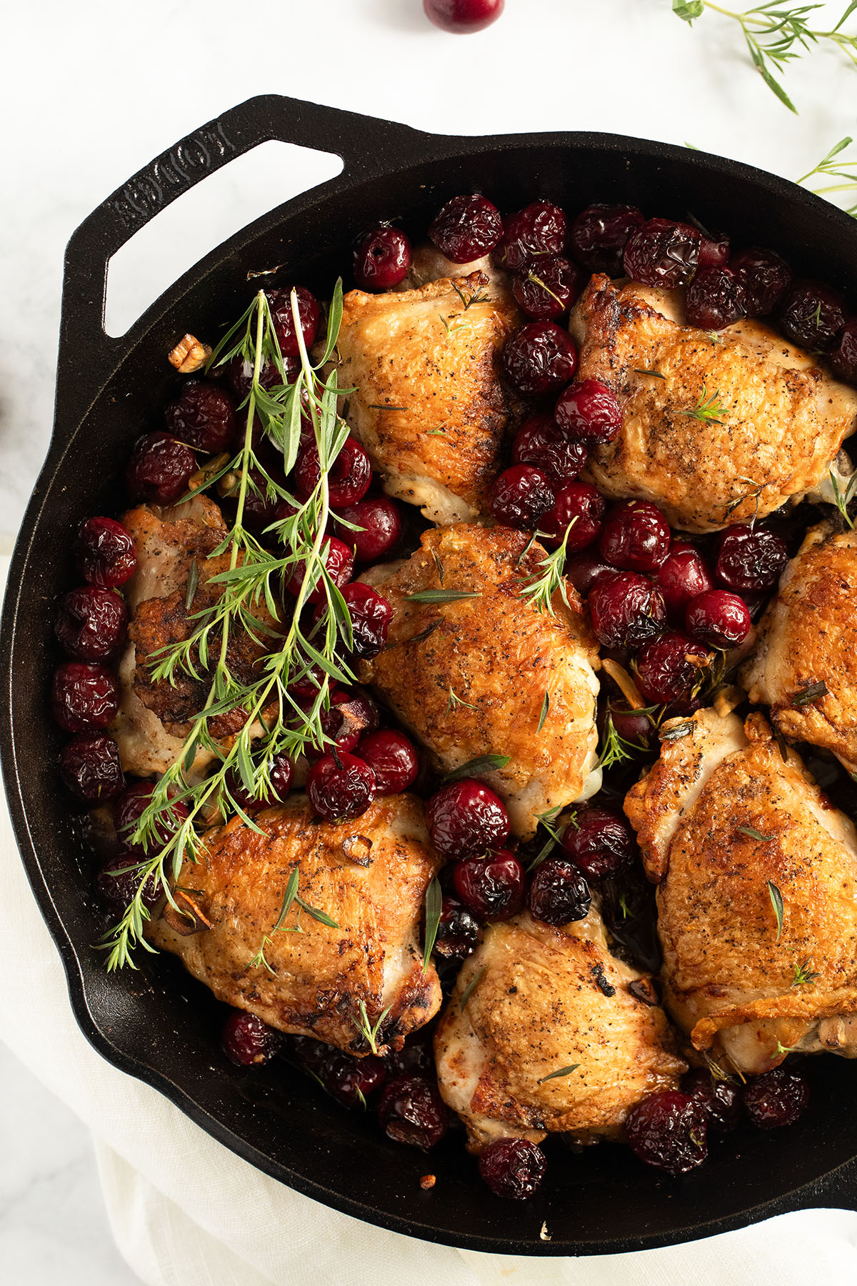 cherry chicken thighs and fresh thyme sprigs in a skillet.