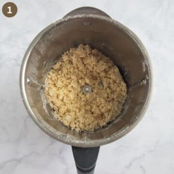 crumbly pastry mixture being pulsed in a food processor.