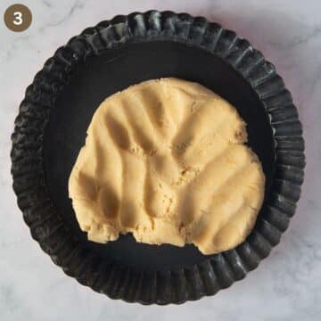 pastry dough pressed in a fluted pie pan, you can see the imprints of the fingers.