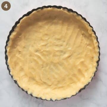 tart pan filled with pressed pastry dough forming the crust, ready for baking.
