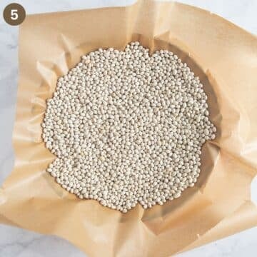tart crust lined with parchment paper and filled with dried beans for blind baking.