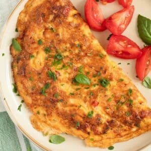 chili omelet sprinkled with parsley and served with tomato wedges and basil.