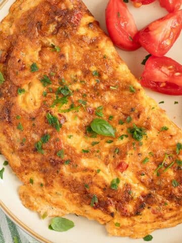 chili omelet sprinkled with parsley and served with tomato wedges and basil.