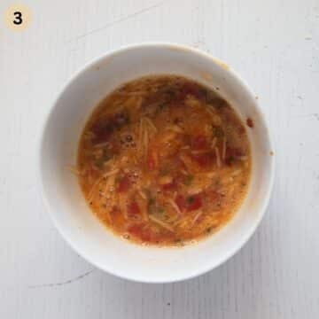 eggs whisked with chilies, tomatoes and cheese in a bowl to make omelette.
