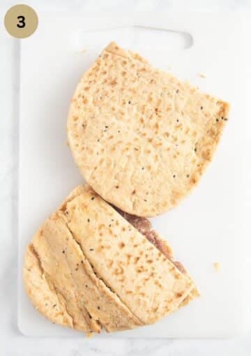 two uncooked pita breads stuffed with lamb filling.