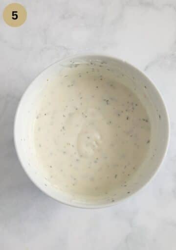 a bowl with yogurt dip with mint and spices.