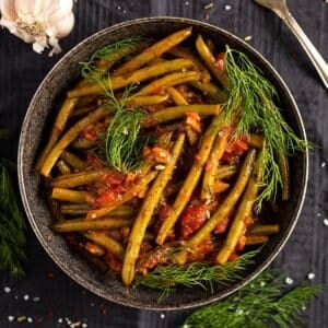 green bean stew topped with fresh dill in a large bowl.