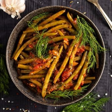 green bean stew topped with fresh dill in a large bowl.