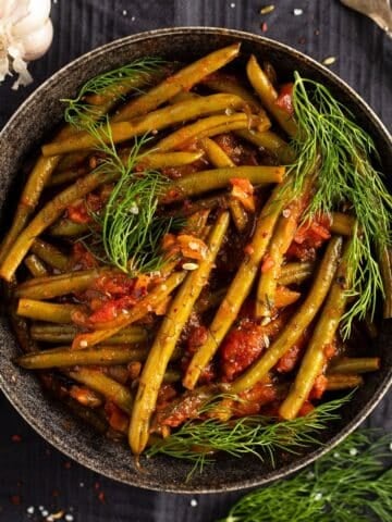 green bean stew topped with fresh dill in a large bowl.