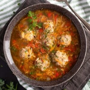 pork meatball souop sprinkled with parsley in a bowl.