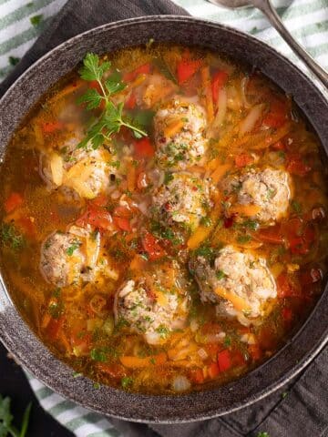 pork meatball souop sprinkled with parsley in a bowl.