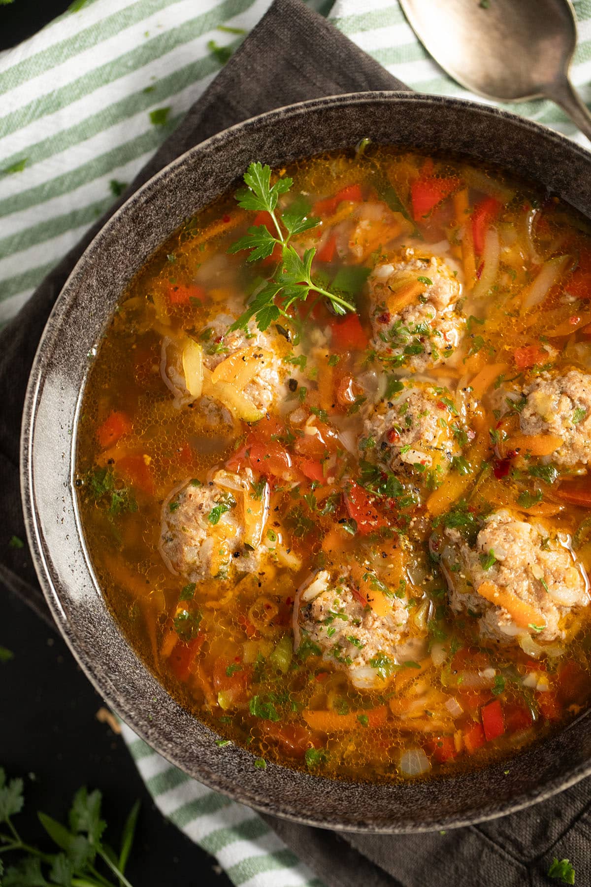 pork meatball soup with zucchini and carrots in a large brown bowl.