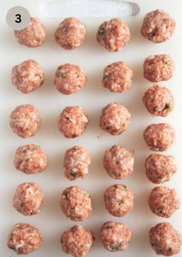 small uncooked pork meatballs for soup on a cutting board.