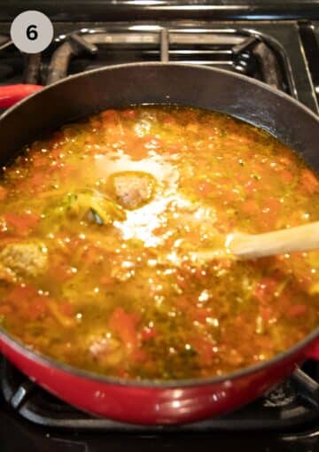 stirring meatballs in soup with a wooden spoon.