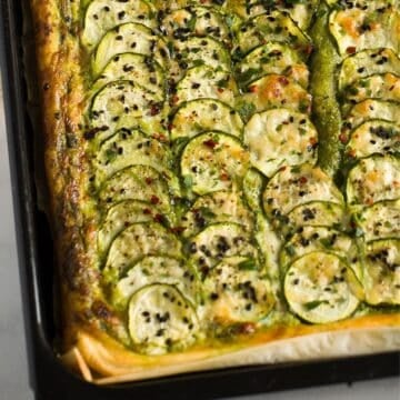 crispy zucchini tart with thin sliced zucchini, and topped with parmesan and black sesame seeds.