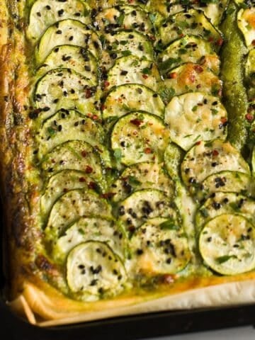 crispy zucchini tart with thin sliced zucchini, and topped with parmesan and black sesame seeds.