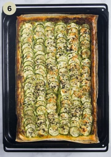 baked tart with thin zucchini slices and parmesan on a baking sheet.