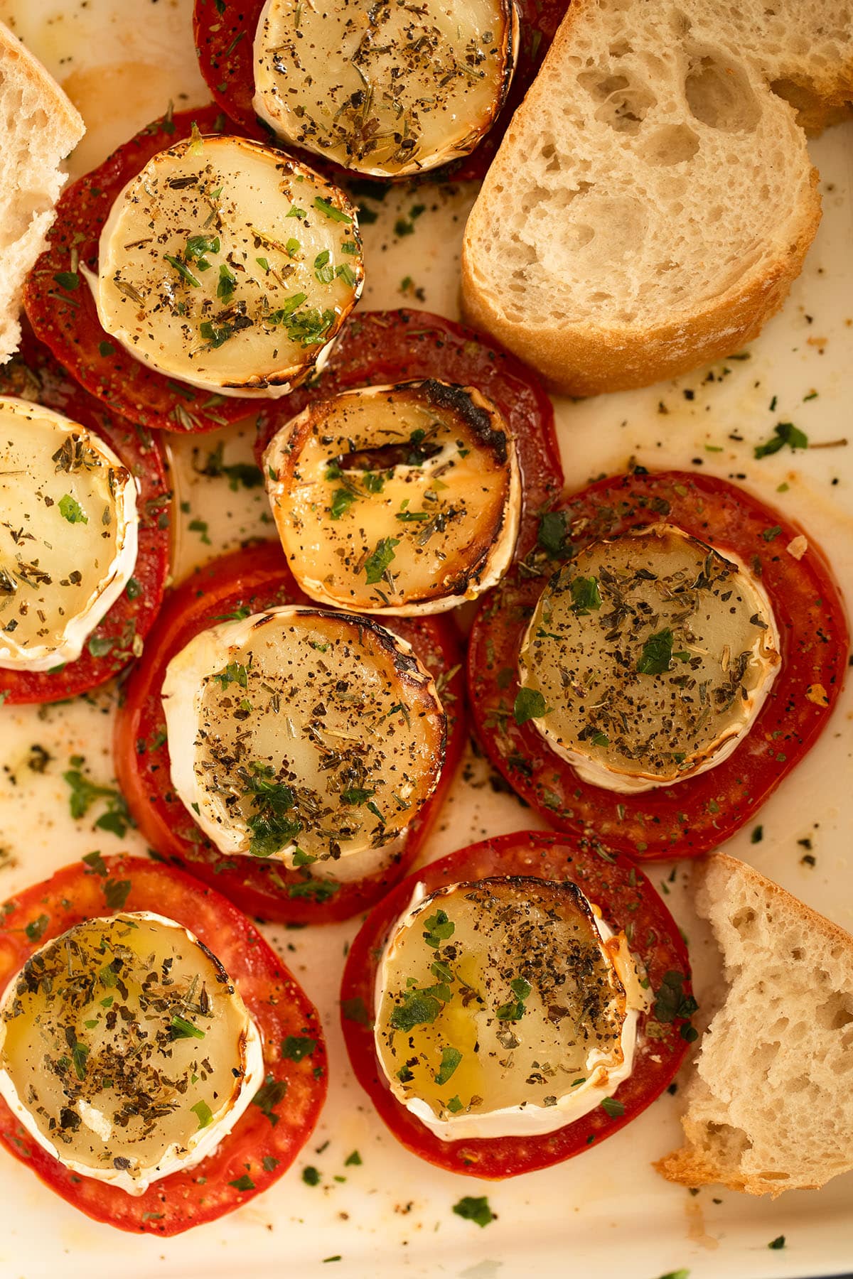 baked goat cheese on tomato slices in a baking dish.