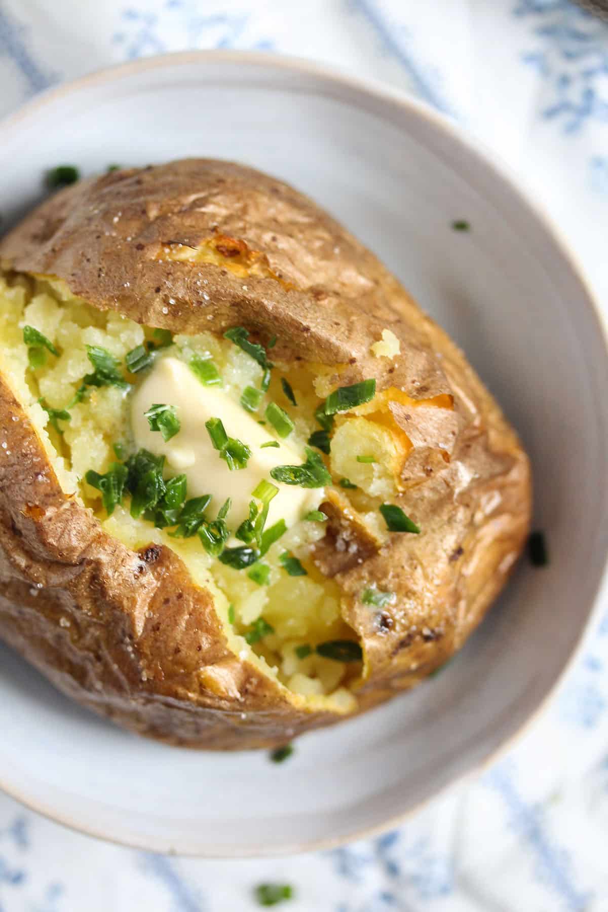 one large baked potato served with butter and sprinkled with chives.