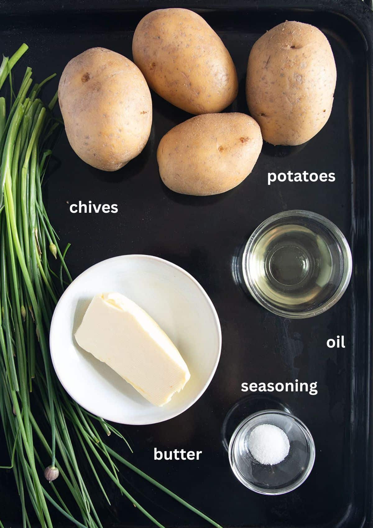 labeled ingredients for making baked potatoes with butter and fresh chives.
