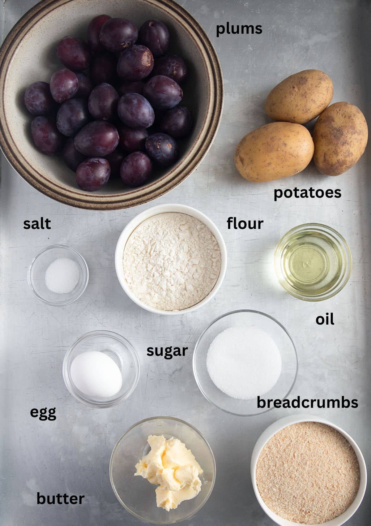 labeled ingredients for making dumplings with plums and potato dough and breadcrumb coating.