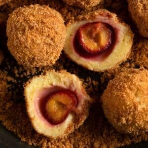 plum dumplings with breadcrumb coating, one cut in the middle to show the plum.