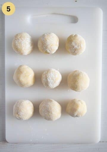 uncooked and floured plum dumplings on a cutting board.