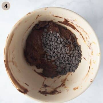 adding chocolate chips to pumpkin muffin batter in a bowl.