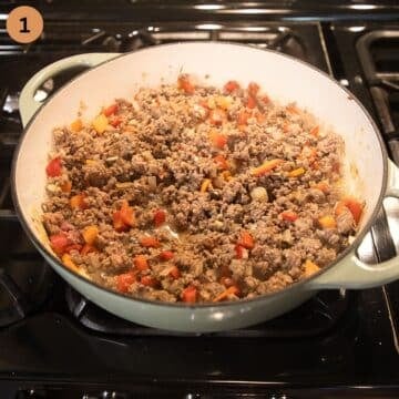 browning ground beef with carrots and peppers in a dutch oven.