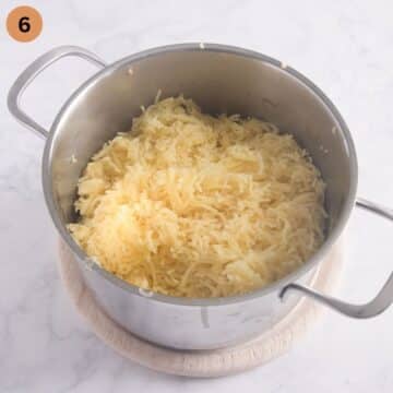 mashed potatoes being mashed with a potato ricer.