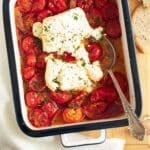 roasted tomatoes and feta in a small baking dish with a spoon in it.