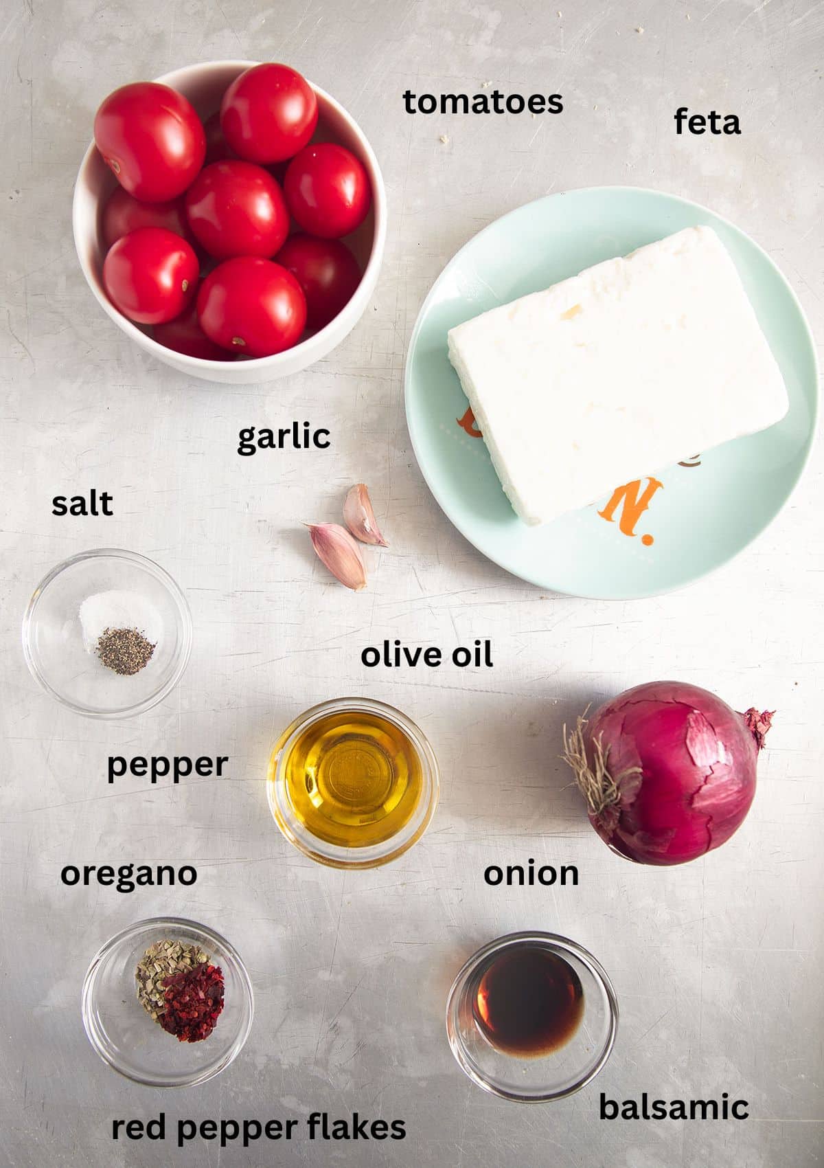 labeled ingredients for roasting tomatoes and a whole piece of feta with oil and seasoning.