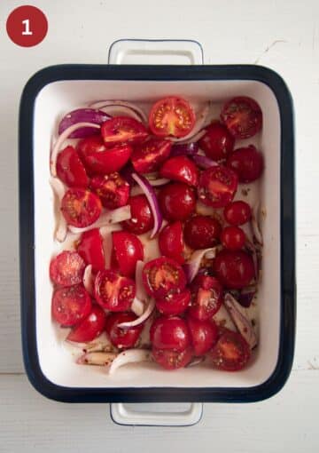 halved cherry tomatoes and red onion slices in a baking dish.