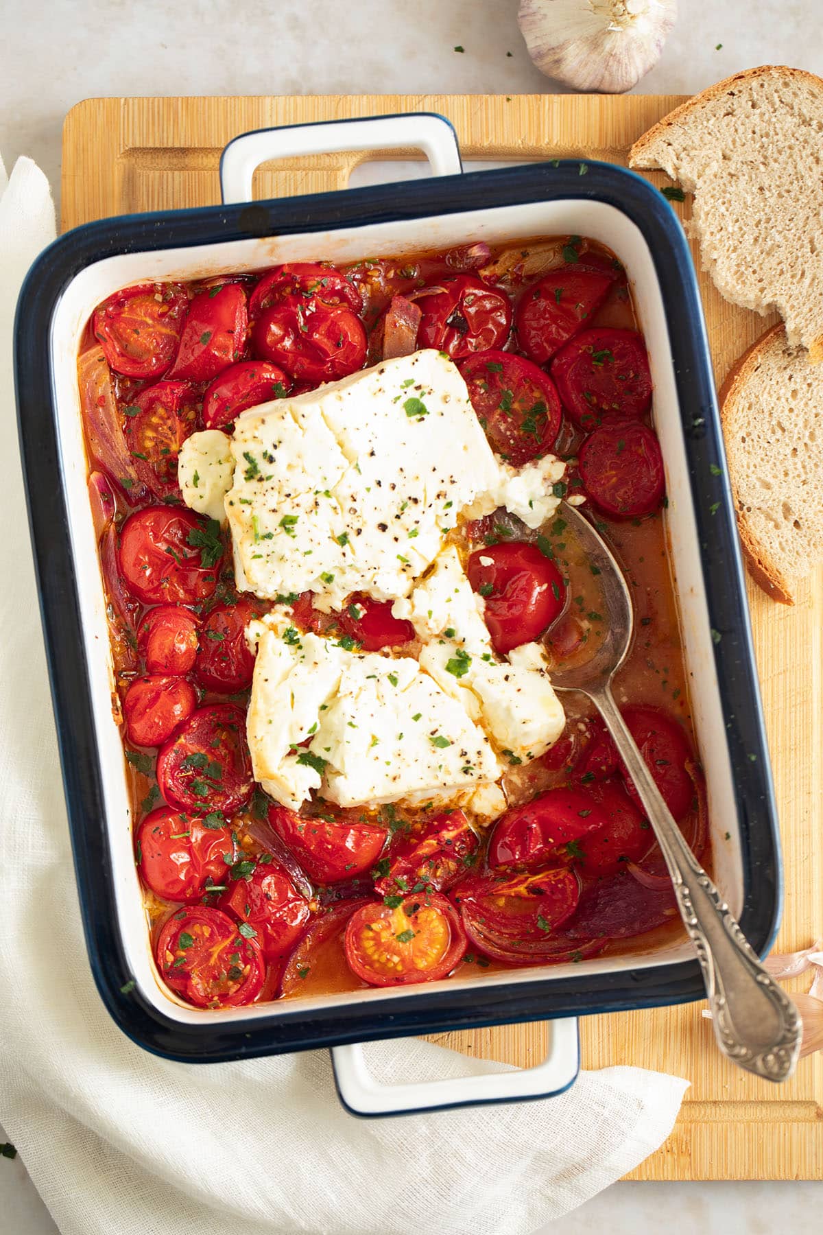roasted feta and tomatoes in a baking dish with a spoon in it.