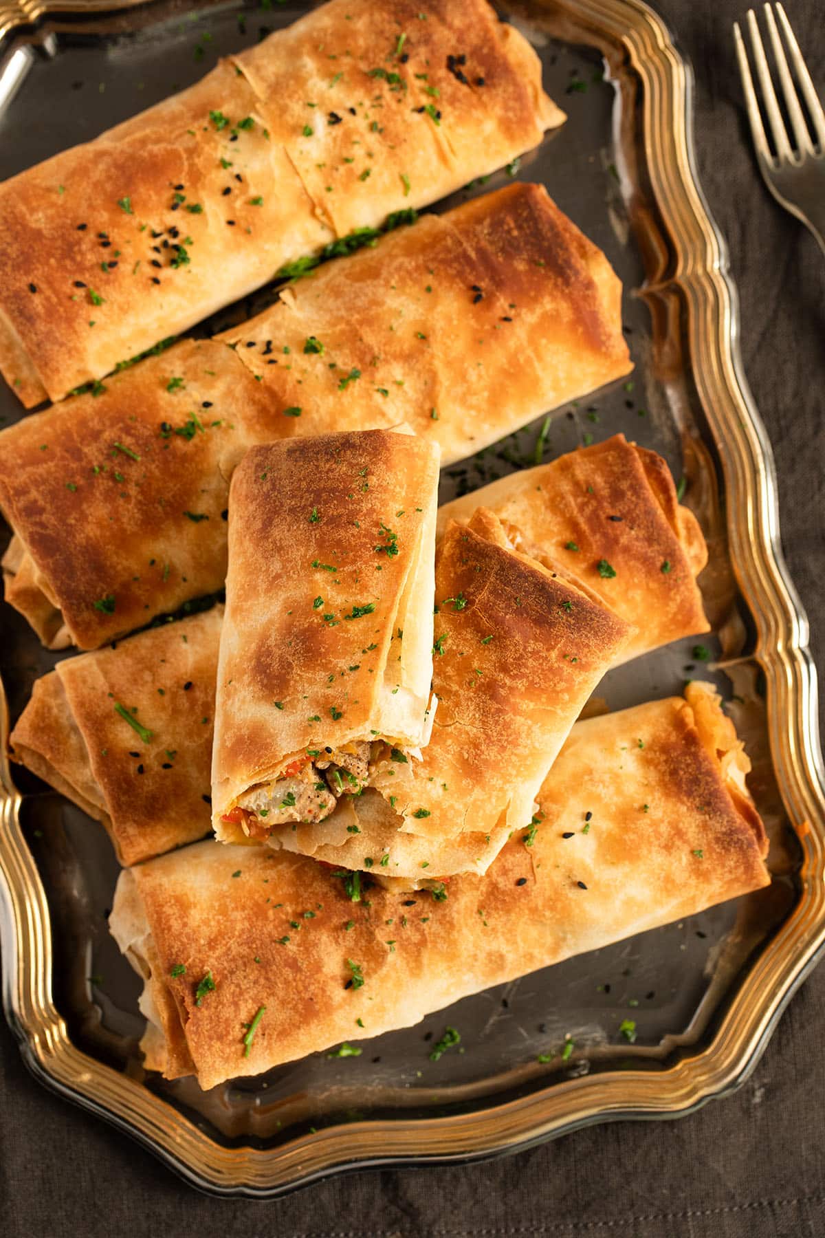 five filo parcels with chicken, one cut in two pieces on a vintage platter.