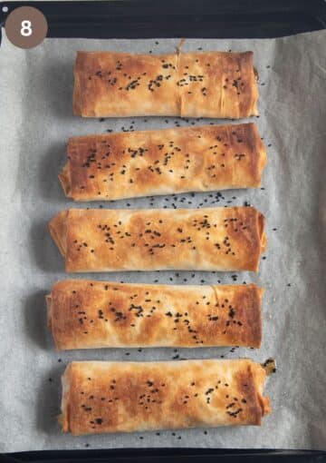 five baked filo parcels with chicken and vegetables on a lined baking sheet.