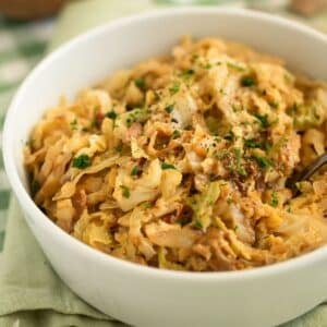 creamy savoy cabbage with bacon and parsley piled in a white bowl.