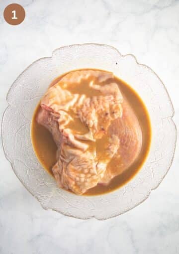 a large skin on turkey breast marinating in a large bowl with honey, soy sauce and mustard mixture.