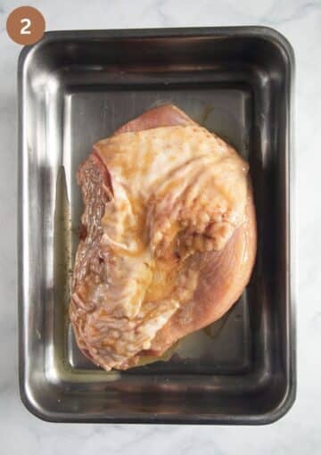 marinated honey turkey breast in a roasting tin before baking.