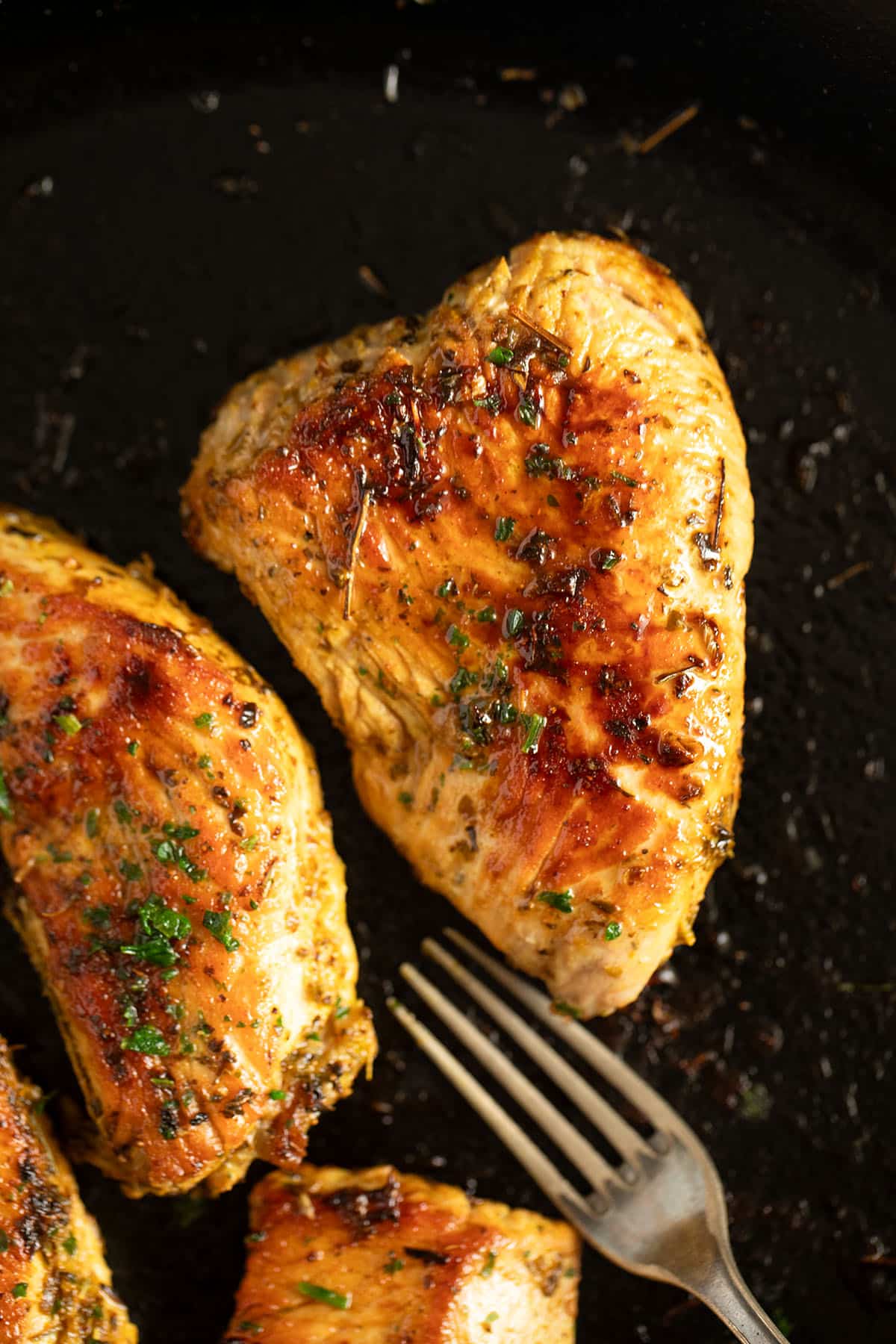 Cooked turkey steaks in a cast iron skillet, golden and ready to serve.