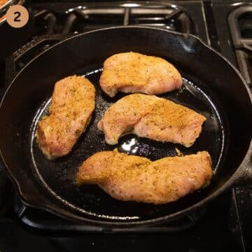 Turkey steaks cooking in a hot skillet, first side searing to golden brown.