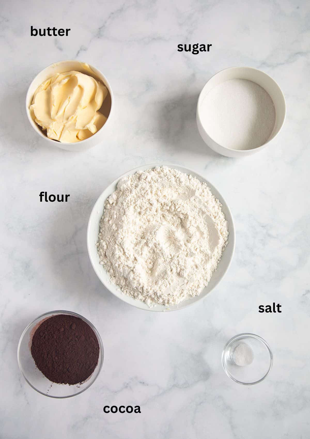 bowls with butter, sugar, flour, cocoa, and salt for making shortbread.