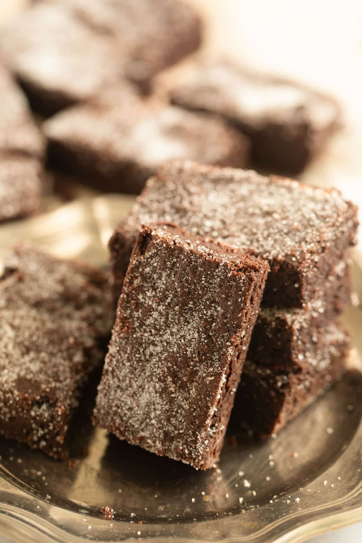 rectangular pieces of cocoa shortbread arranged on a plate, one leaning on the others and many more pieces behind.