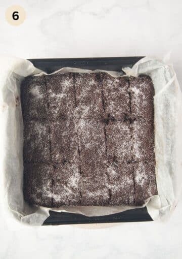 cocoa shortbread cut into rectangles and sprinkled with granulated sugar in a baking dish lined with parchment paper.