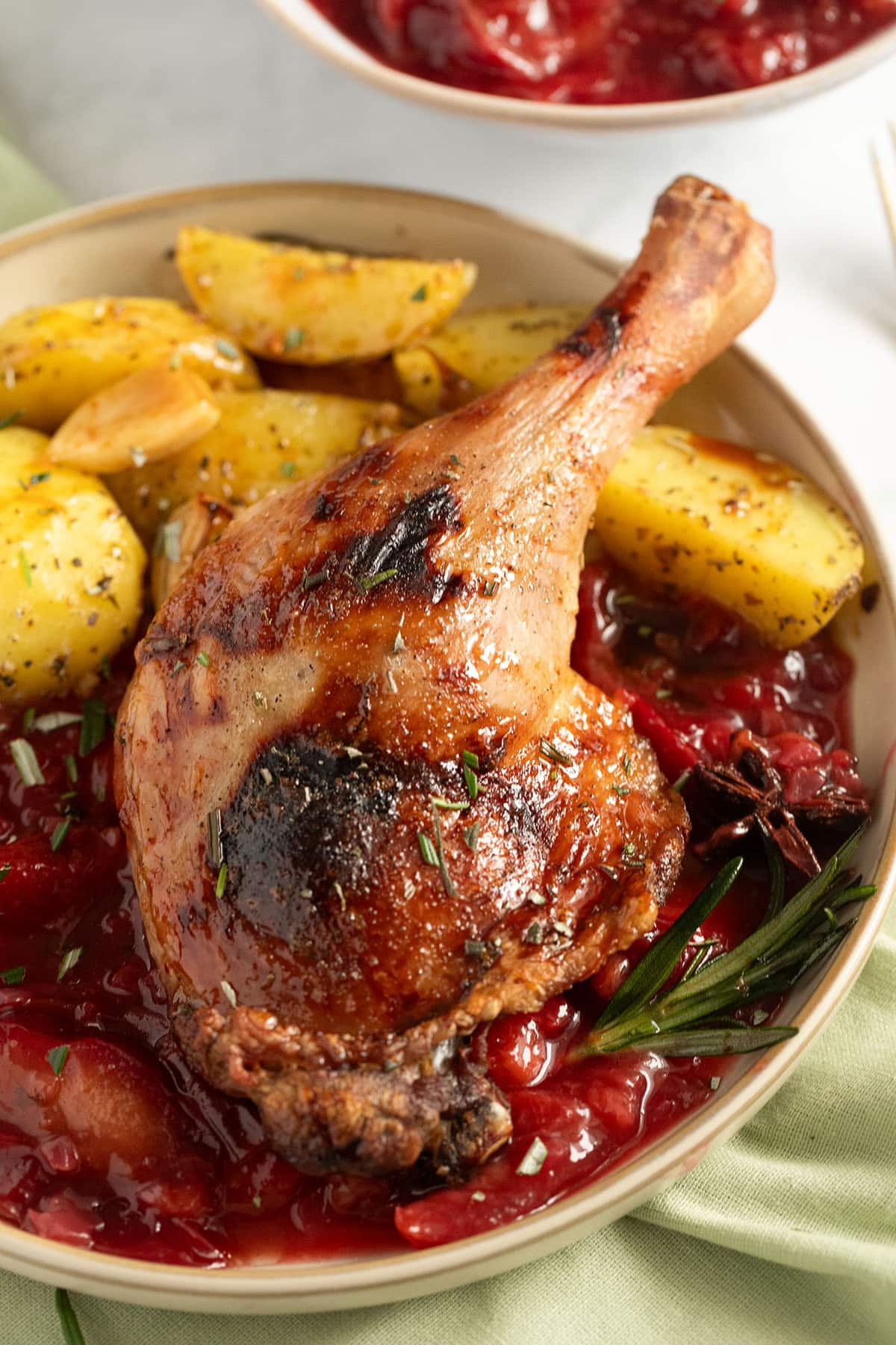 plum sauce with duck and potatoes served on a plate.