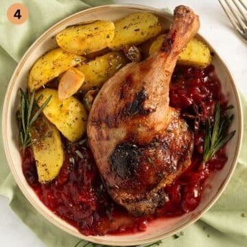 one roasted duck legs served on plum sauce with potatoes.