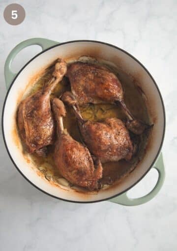 four slow cooked duck legs in a pot.