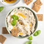 sun-dried tomatoe cream cheese garnished with a drizzrle of oil and basil and served with small crackers.