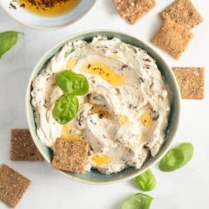 sun-dried tomatoe cream cheese garnished with a drizzrle of oil and basil and served with small crackers.