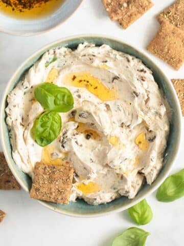 sun-dried tomatoe cream cheese garnished with a drizzrle of oil and basil and served with small crackers.